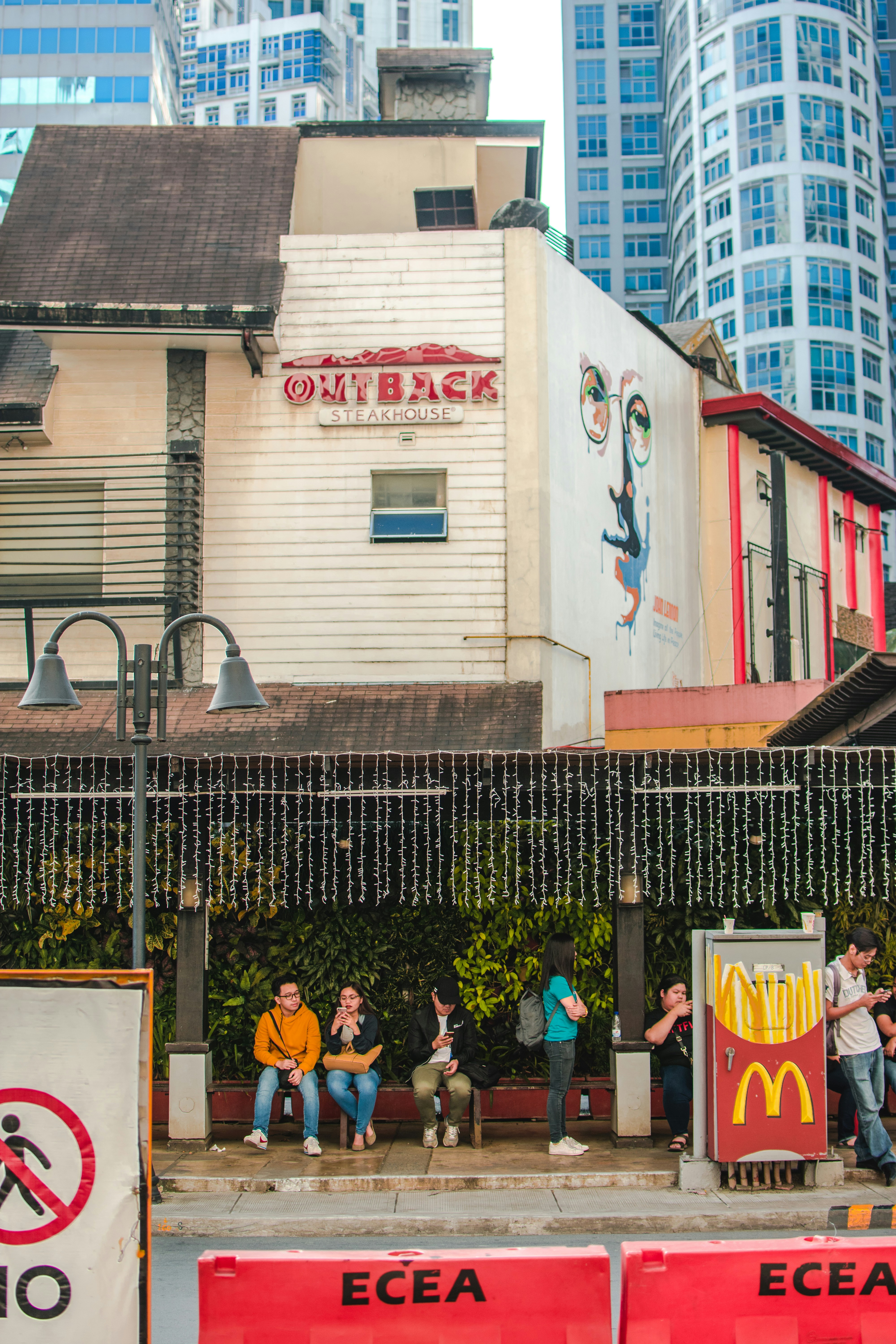 people sitting on bench near red and white concrete building during daytime