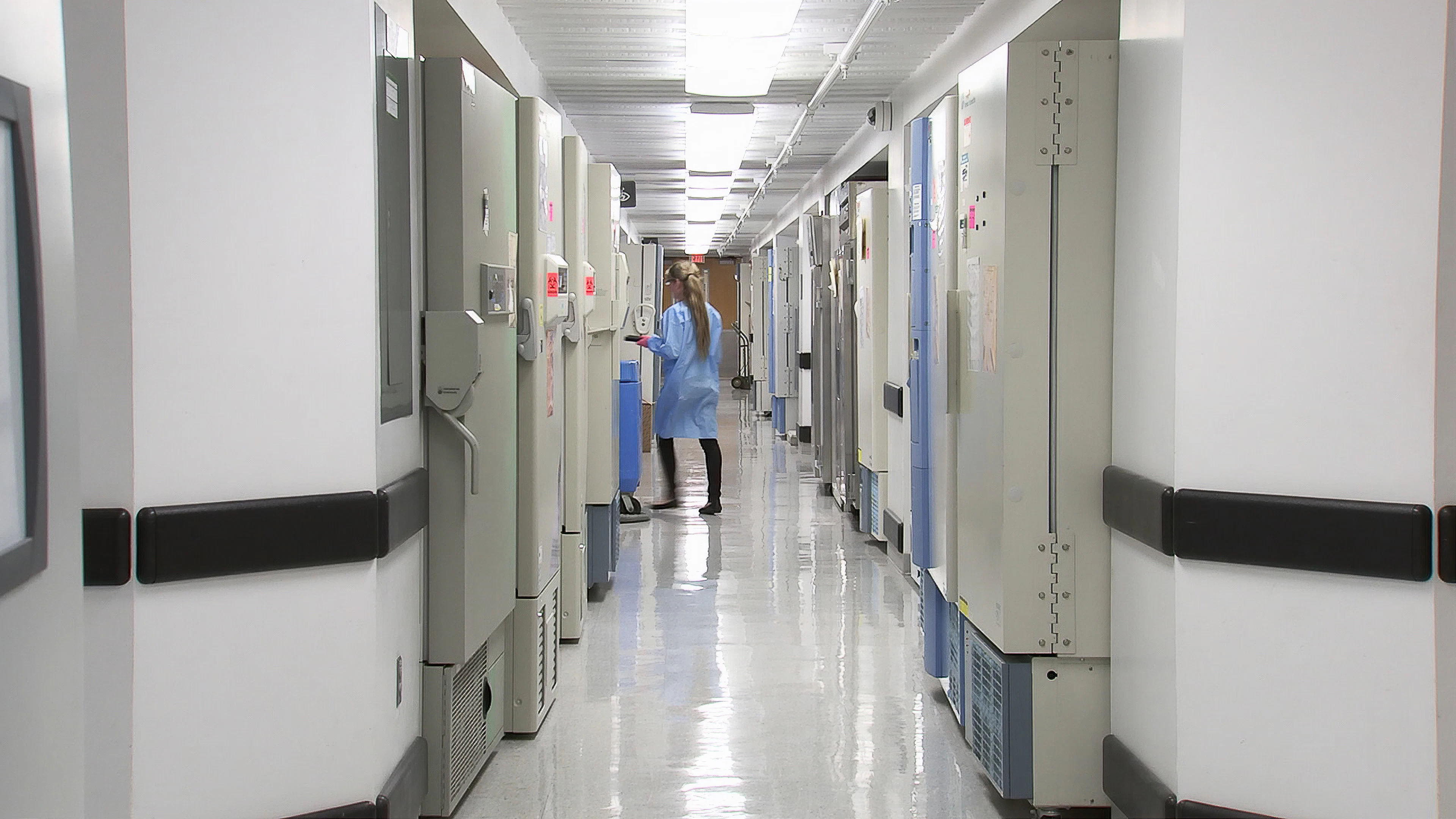A clinician walking down a bright hospital corridor