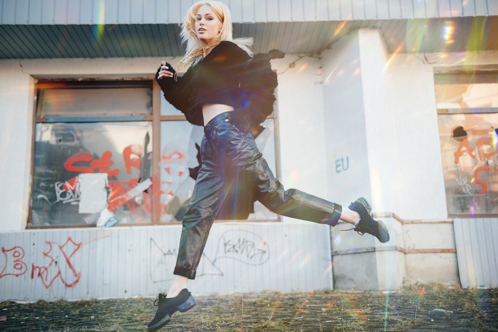 woman in black leather jacket and black pants jumping on air