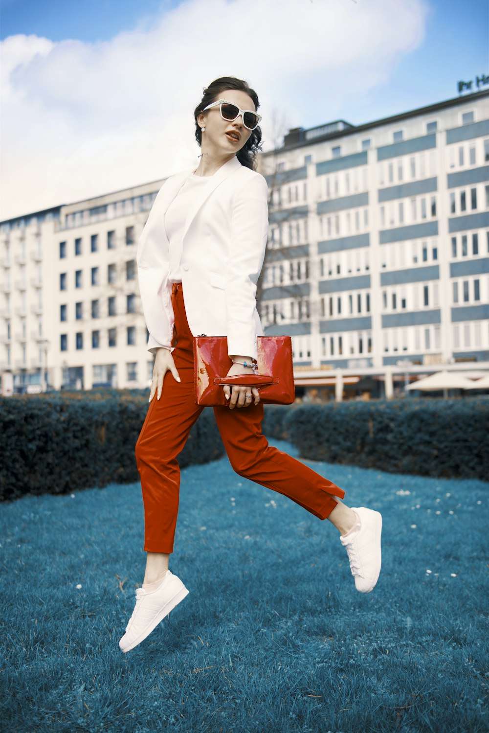 woman in white long sleeve shirt and brown pants standing on green grass field during daytime