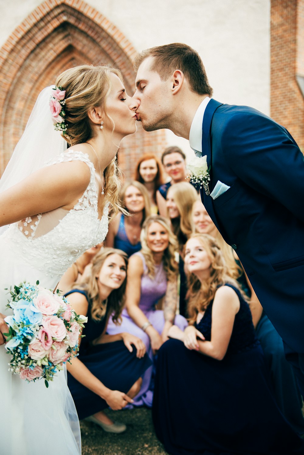 man in black suit jacket kissing woman in white wedding dress