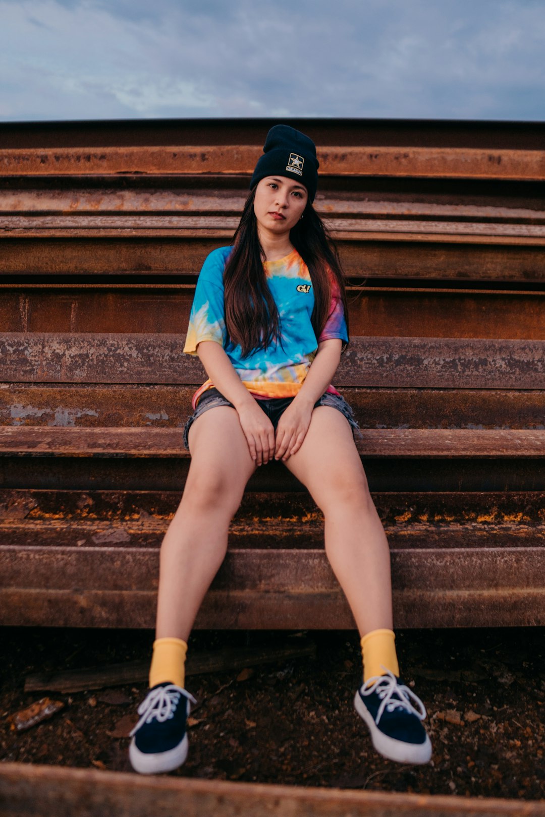 woman in blue shirt and black shorts sitting on brown concrete stairs