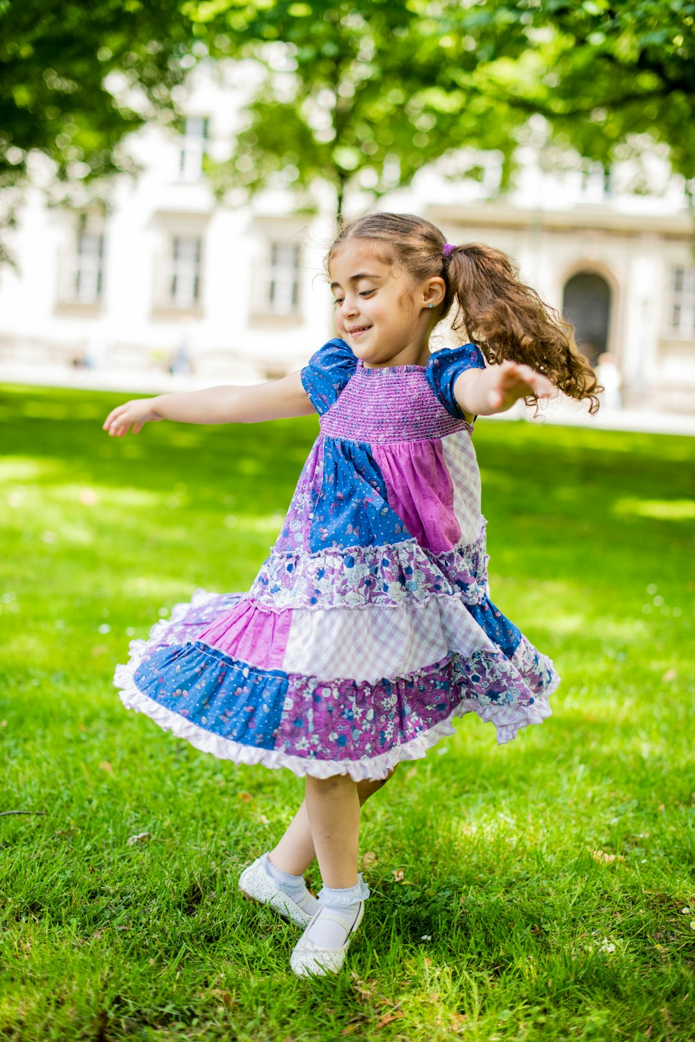 girl in purple and pink dress standing on green grass field during daytime