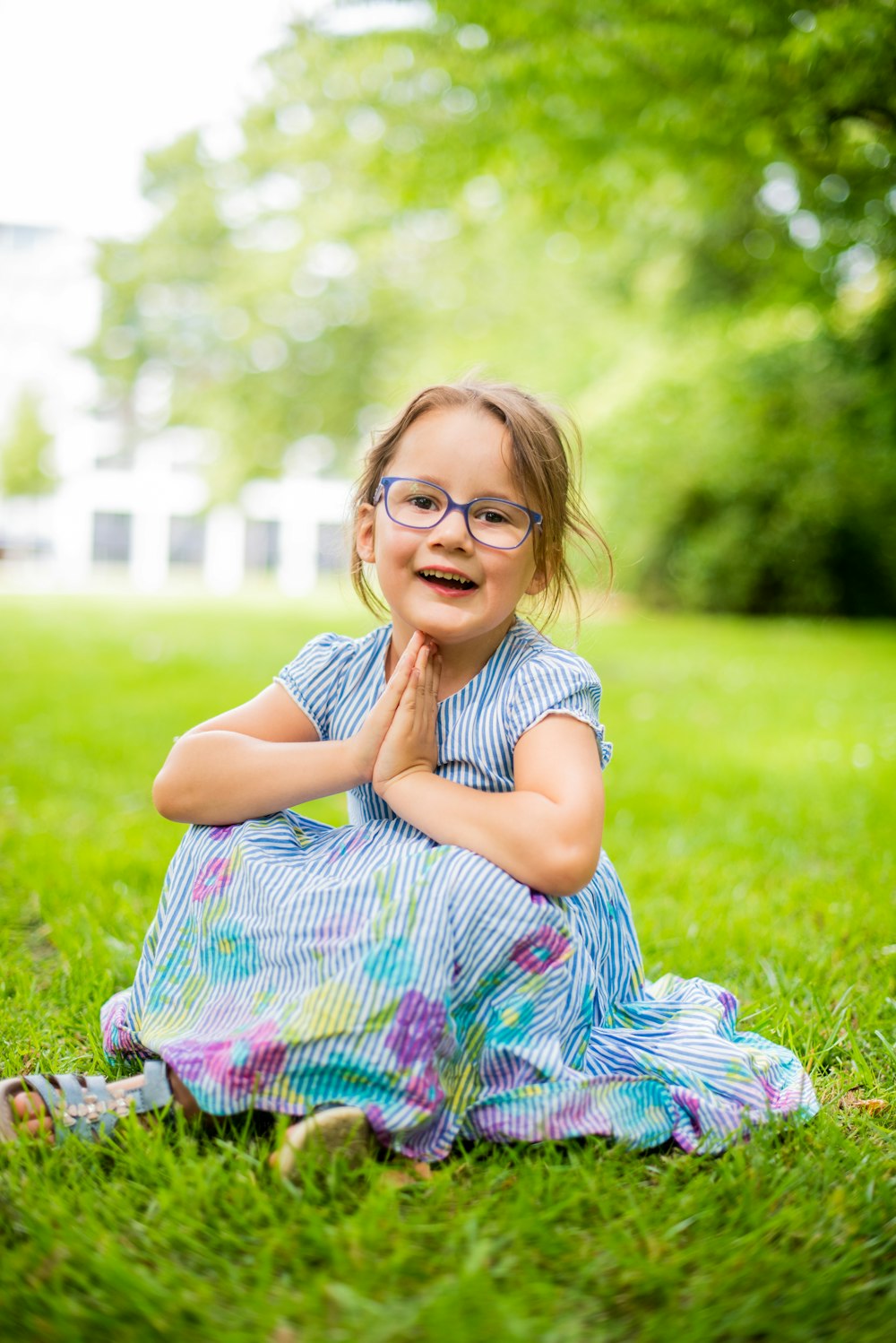 girl in blue and white stripe dress lying on green grass field during daytime