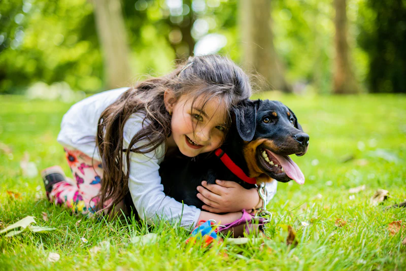 A girl smiling with her arms around her dog in the grass