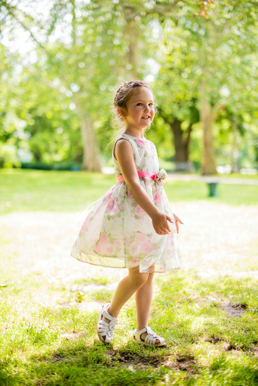 girl in pink and white floral dress standing on green grass field during daytime