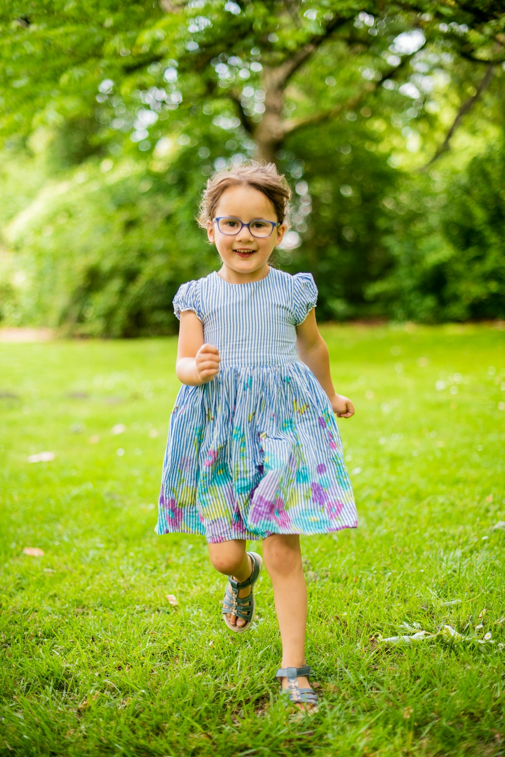 girl in blue and white polka dot dress standing on green grass field during daytime