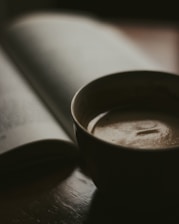 Cozy coffee cup on a wooden table next to an open book inside a classic theater bookstore.