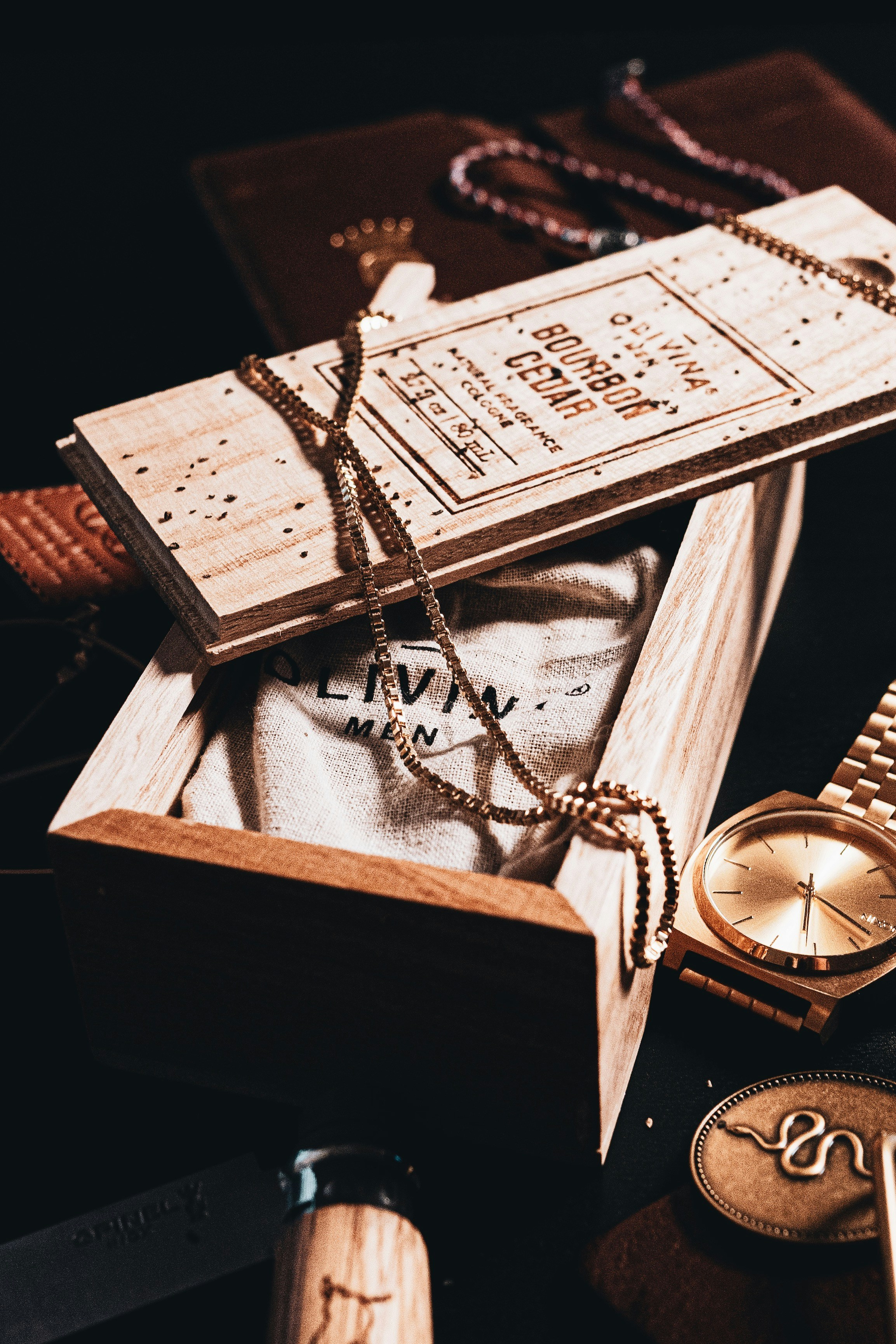 Gold watch, chain, cologne box, and pocket knife arranged stylishly.