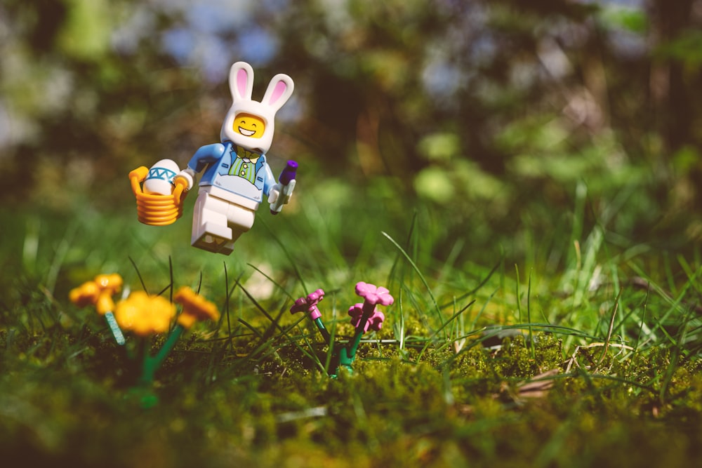 a toy rabbit holding a watering can in the grass