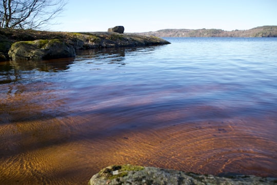brown rock formation on body of water during daytime in Lygnern Sweden
