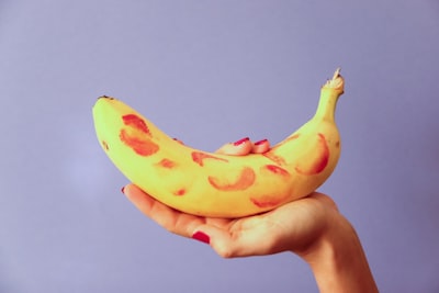person holding yellow banana fruit sensual teams background
