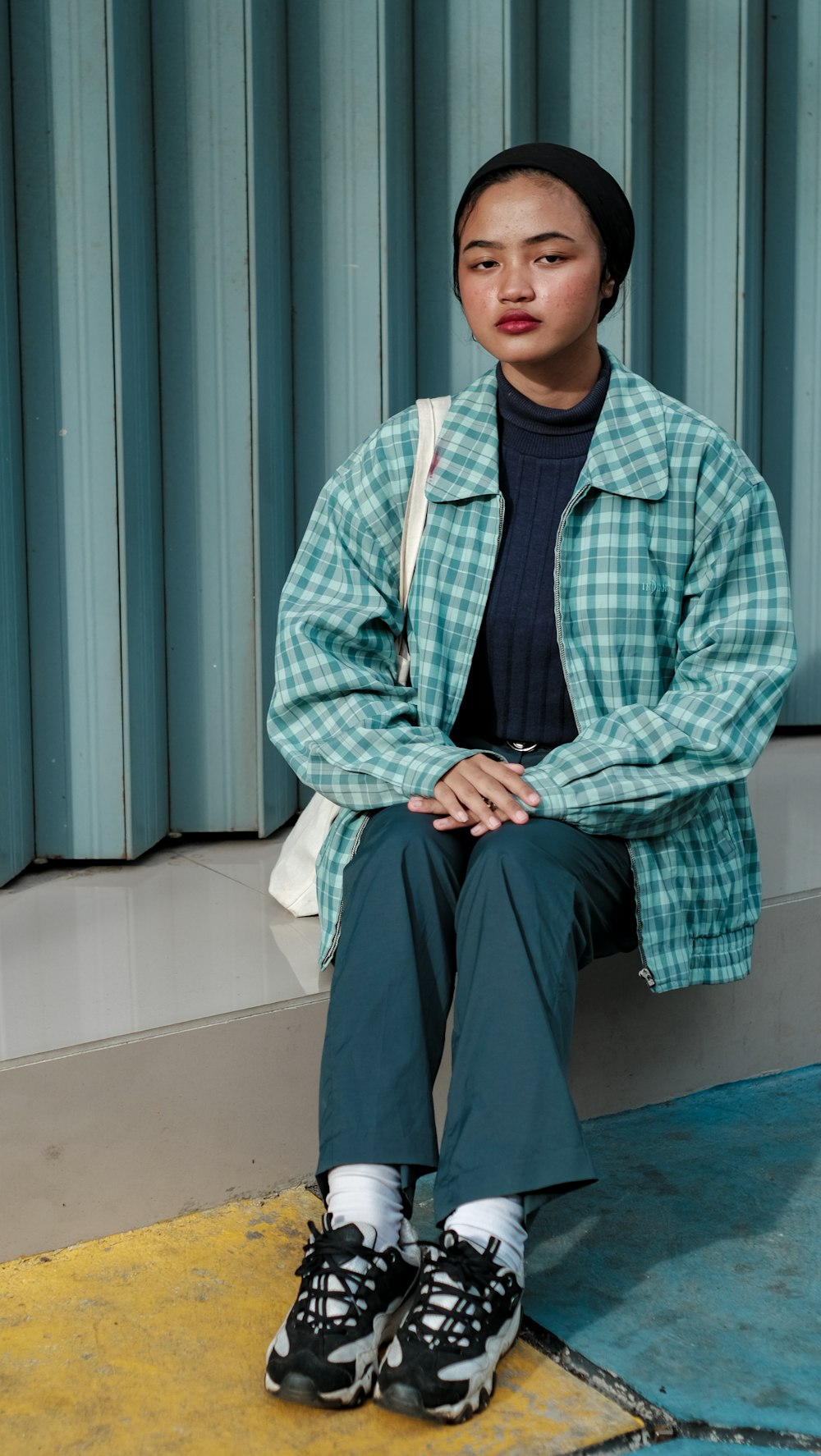 man in blue and white plaid dress shirt and black pants sitting on blue floor