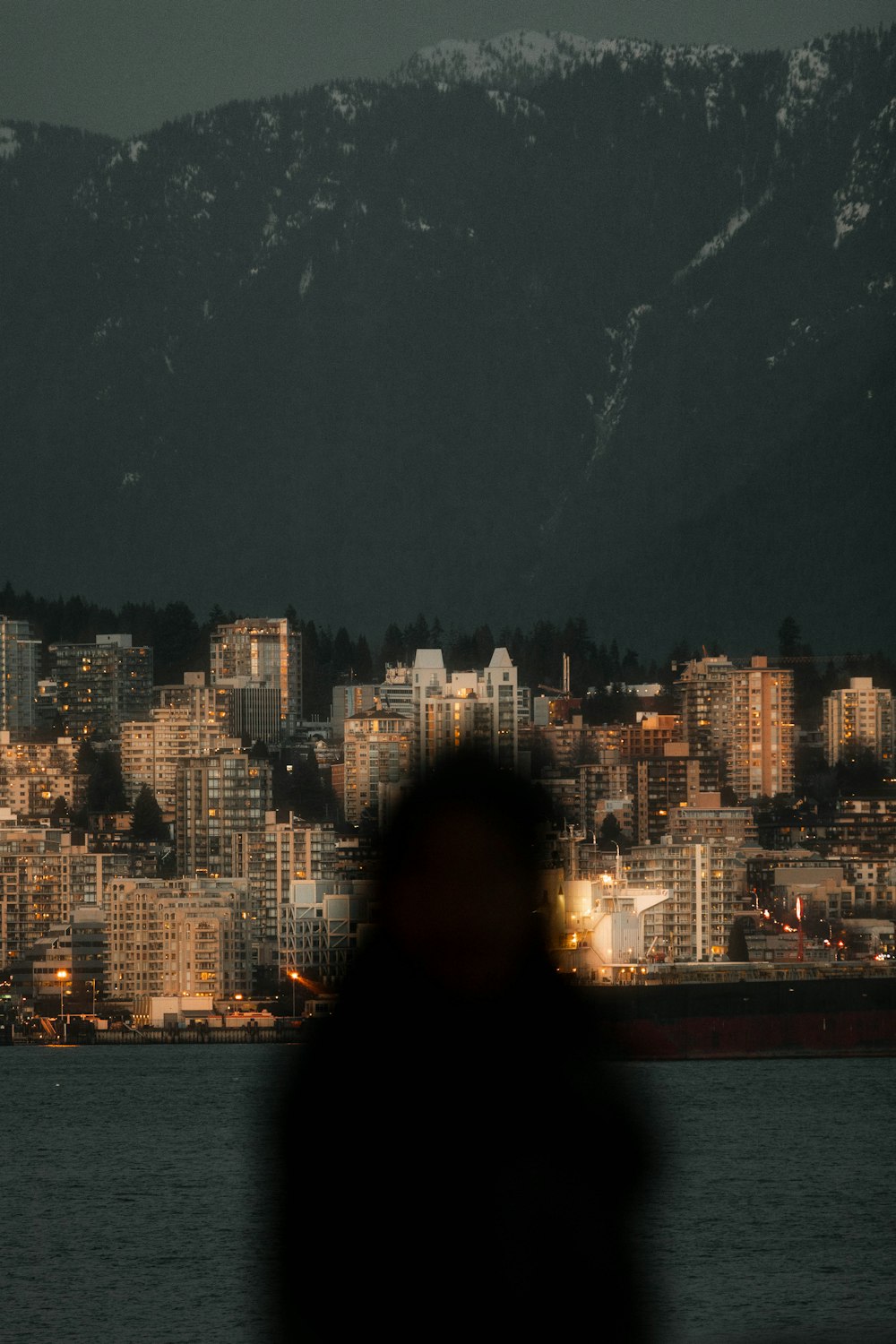 woman in black hoodie standing near body of water during daytime