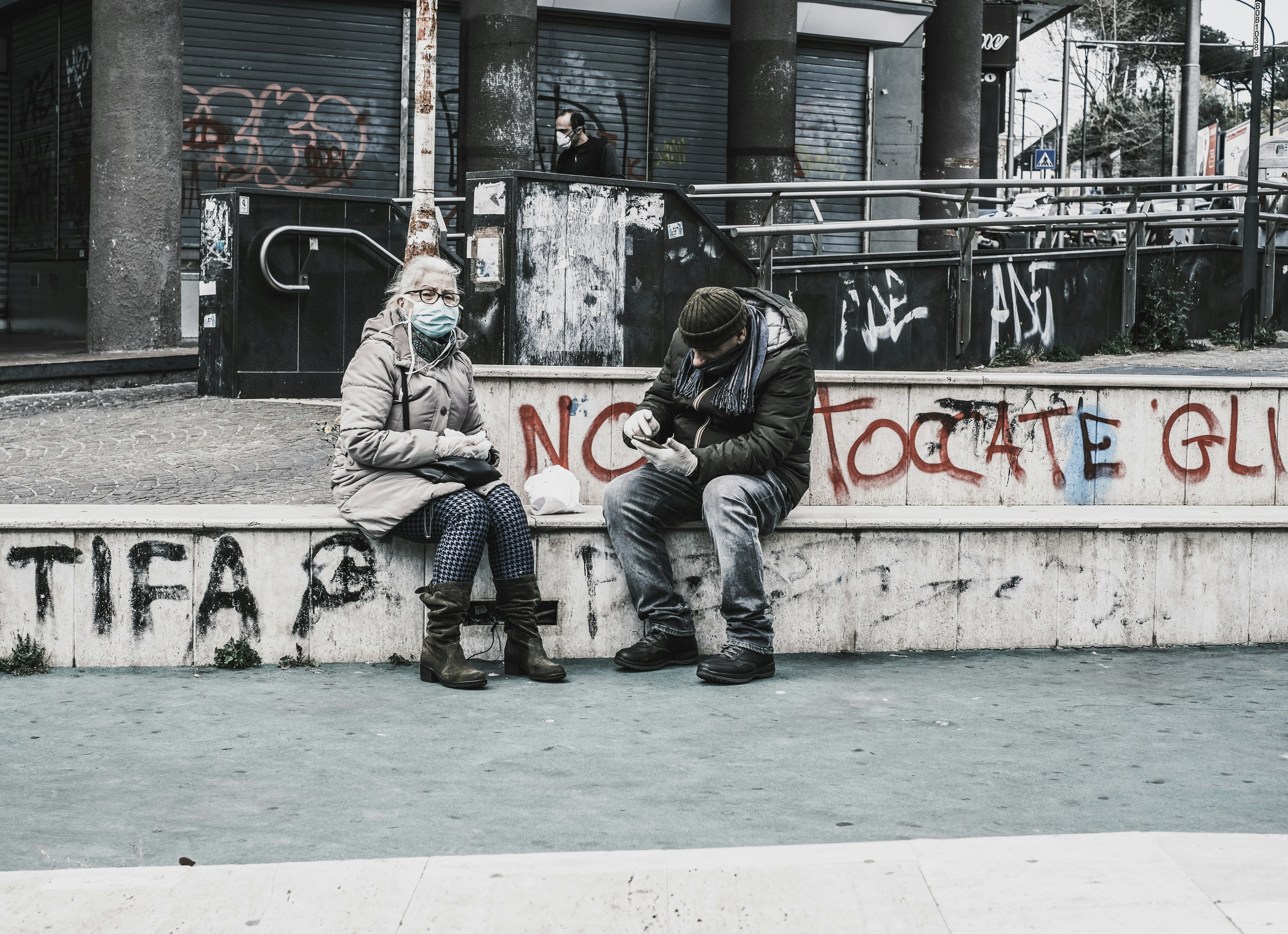 man in black leather jacket and pants sitting on concrete bench