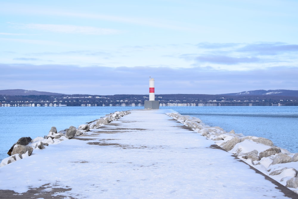 white and red lighthouse on gray concrete dock during daytime