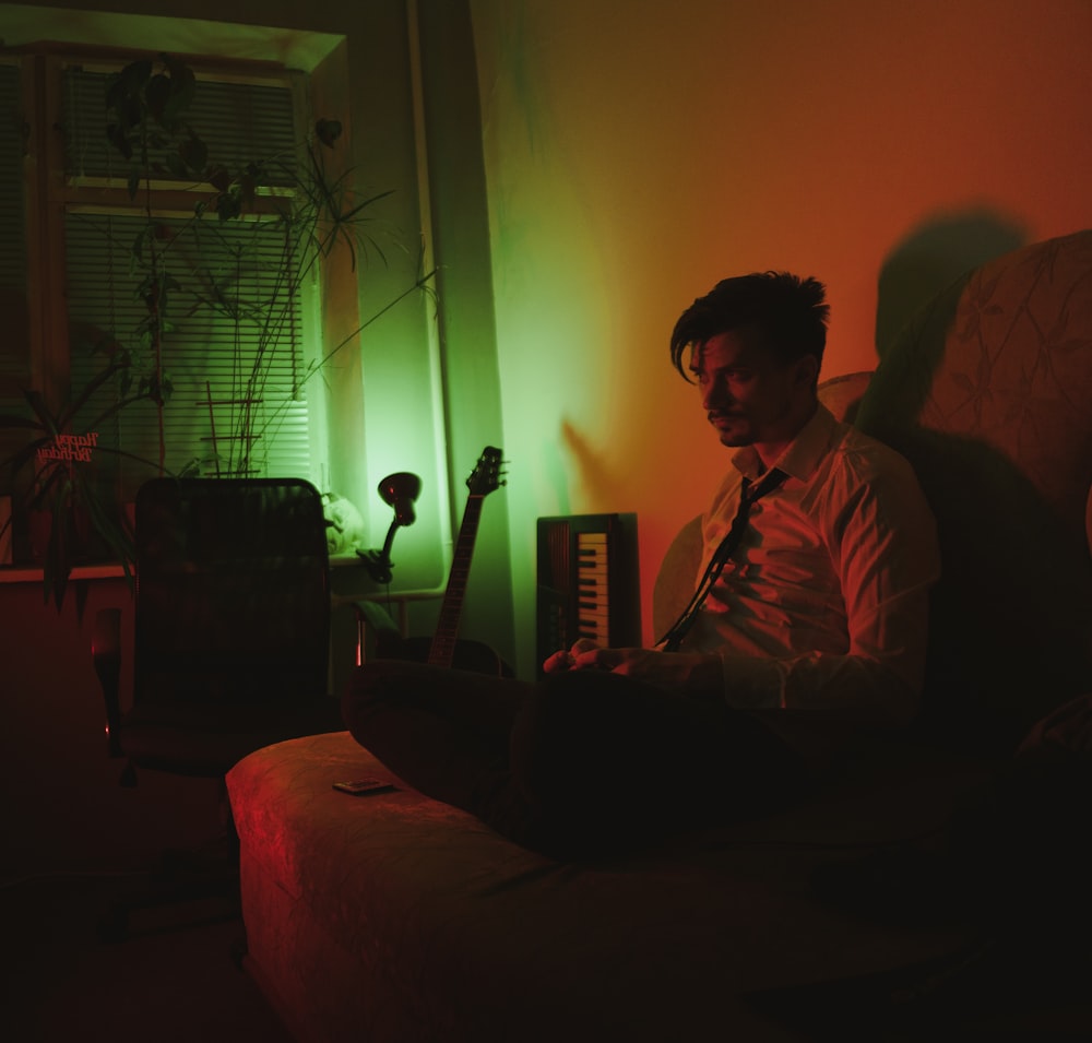 man in red dress shirt sitting on couch