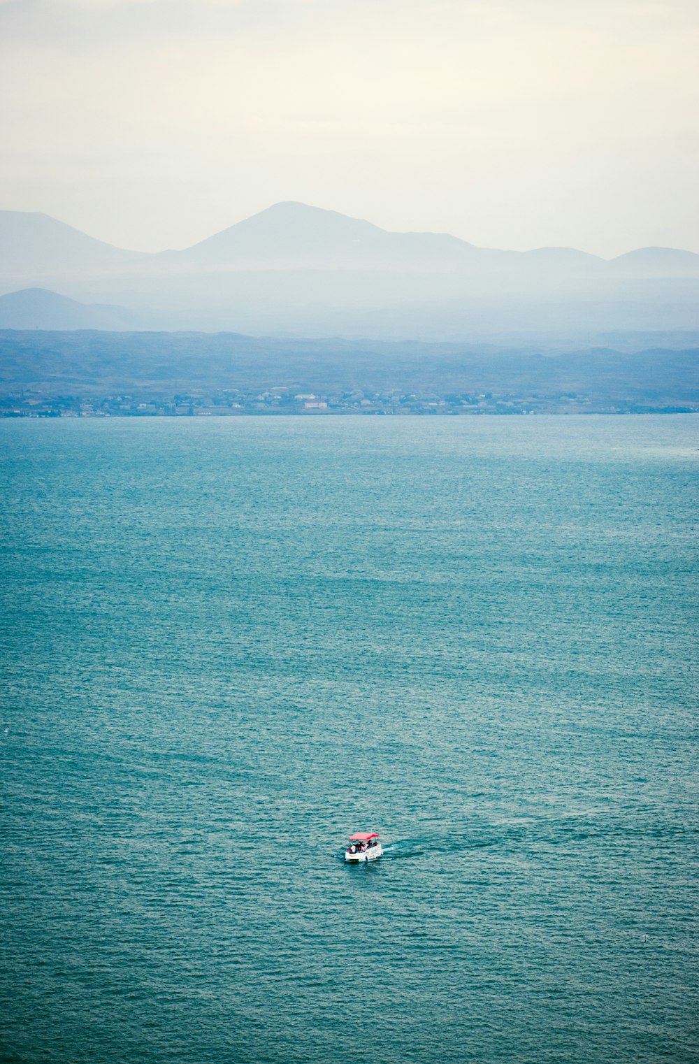 person in red shirt riding on red boat on sea during daytime