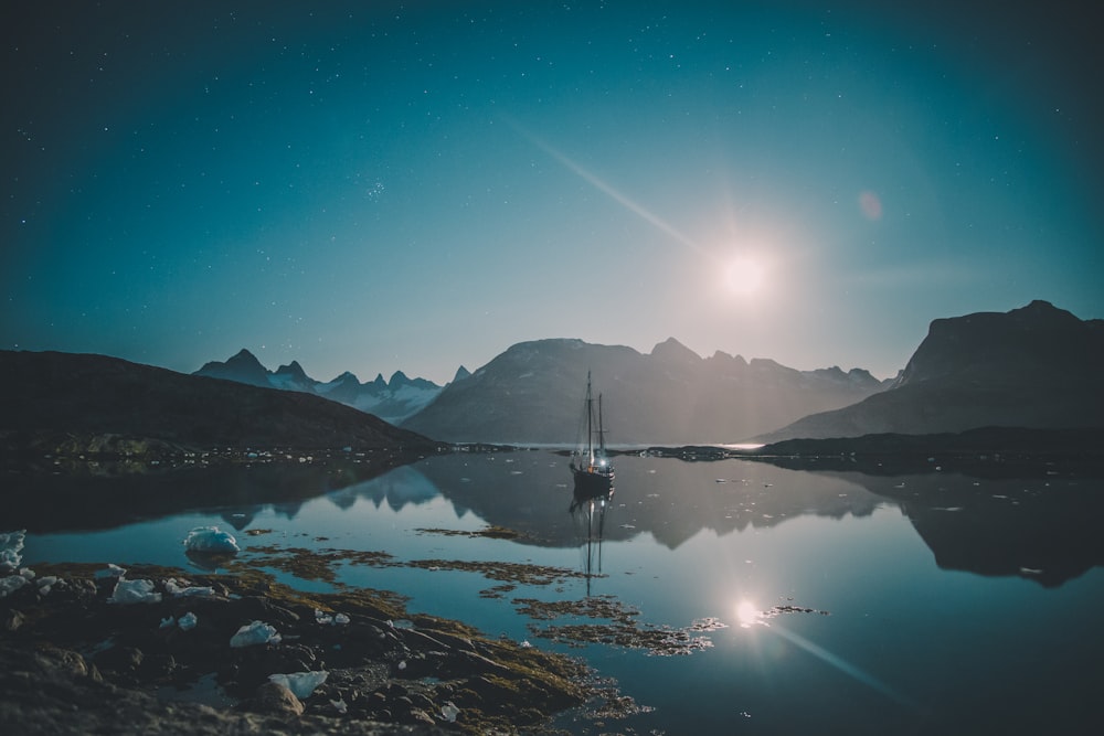 body of water near mountain during night time