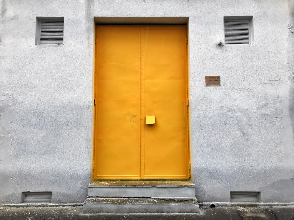 yellow wooden door on gray concrete wall