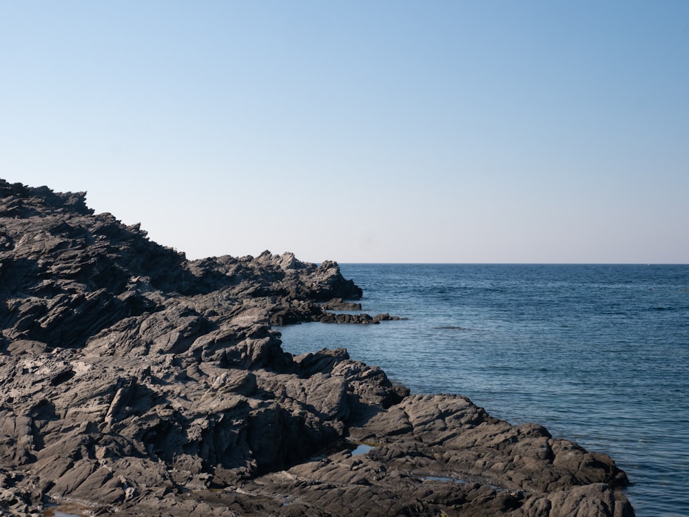 black rock formation near body of water during daytime