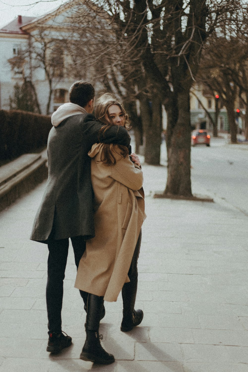 woman in brown coat and black pants standing on sidewalk during daytime