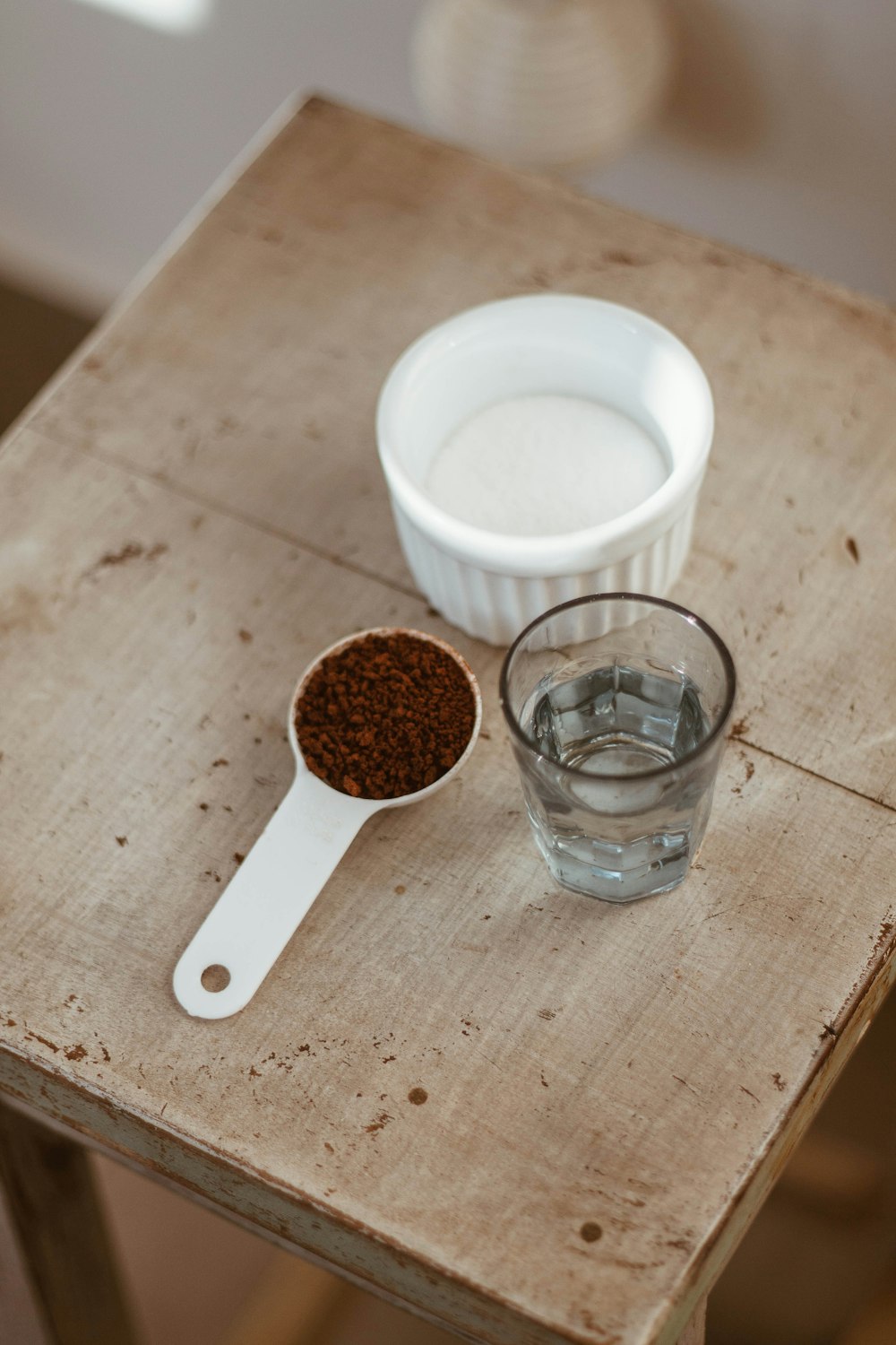 Taza de cerámica blanca junto a un vaso transparente sobre una mesa de madera marrón