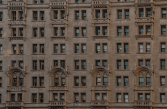 A facade of a classic architectural building with multiple evenly spaced windows and ornate decorative details. The stone exterior exudes an historic and elegant appearance.