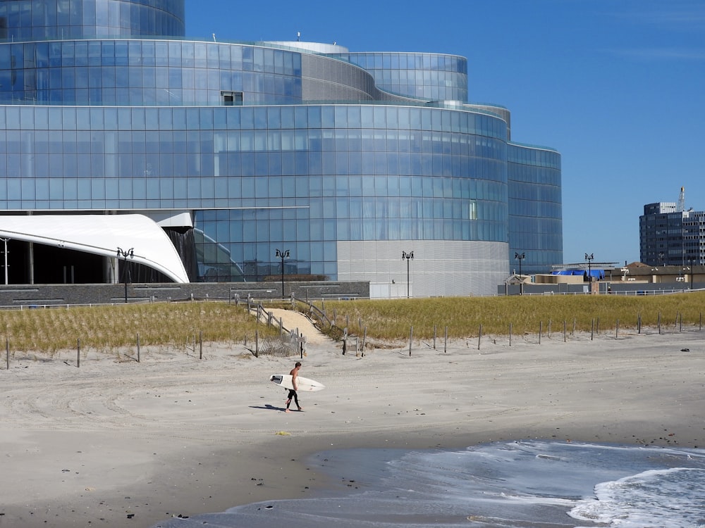 Menschen, die tagsüber auf grauem Sand in der Nähe von White Building spazieren gehen