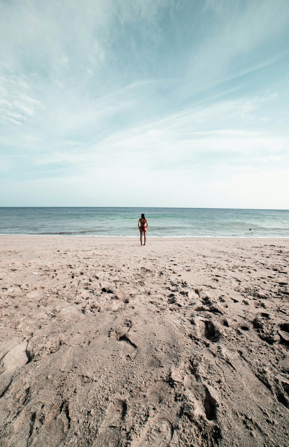 woman in black bikini walking on beach during daytime