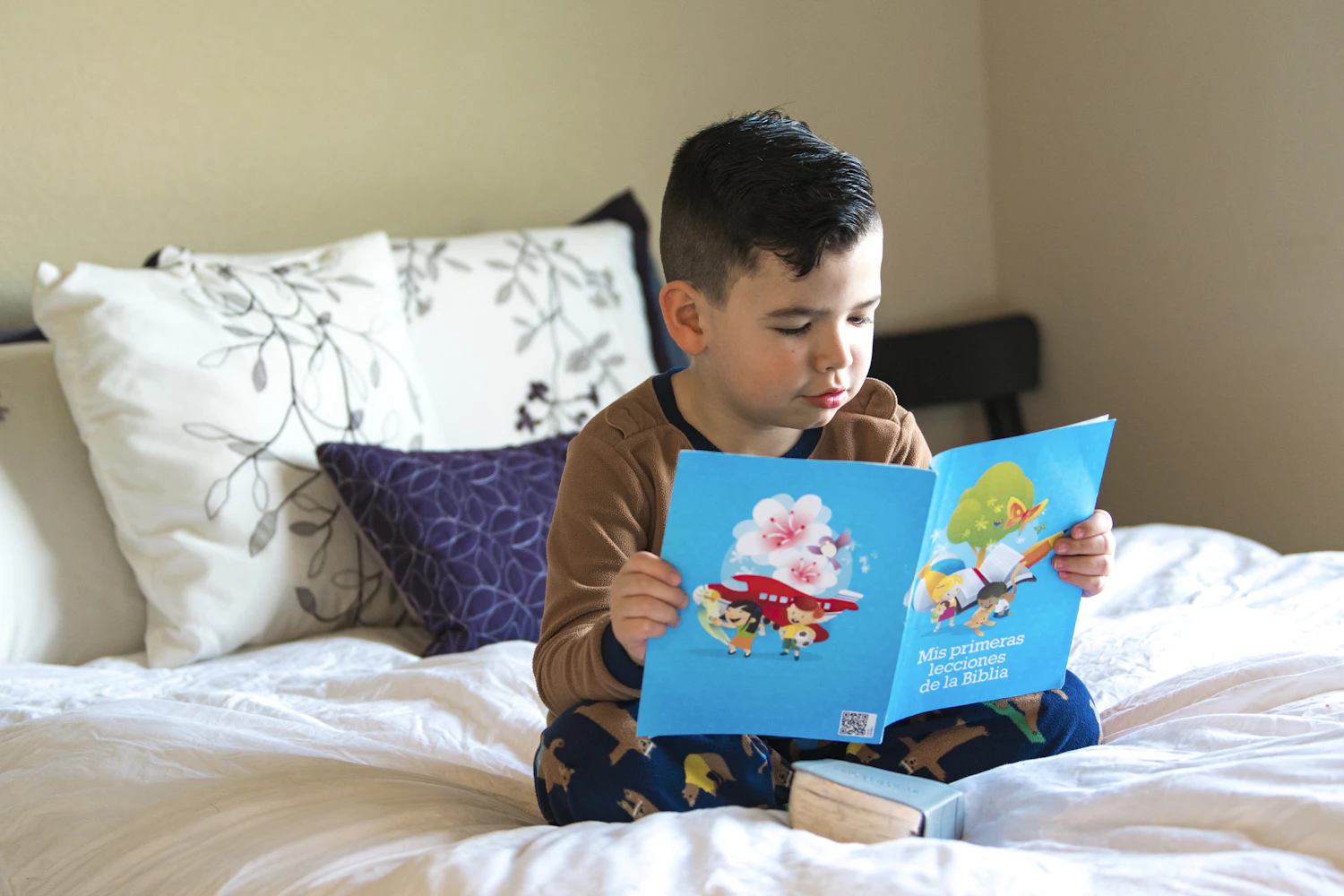 Boy sitting cross-legged with a picture book, thinking before he speaks