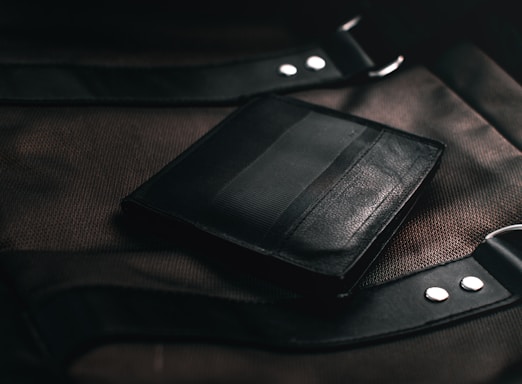 black leather bifold wallet on brown textile