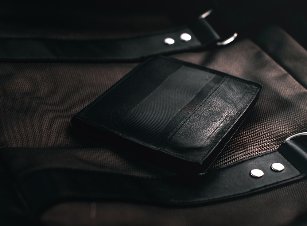 black leather bifold wallet on brown textile