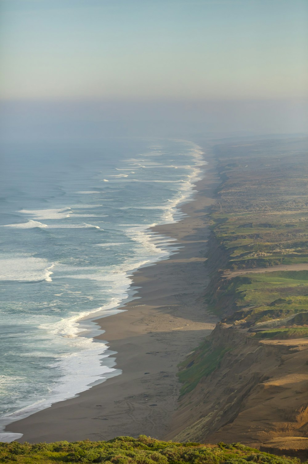 aerial view of green and brown land near body of water during daytime