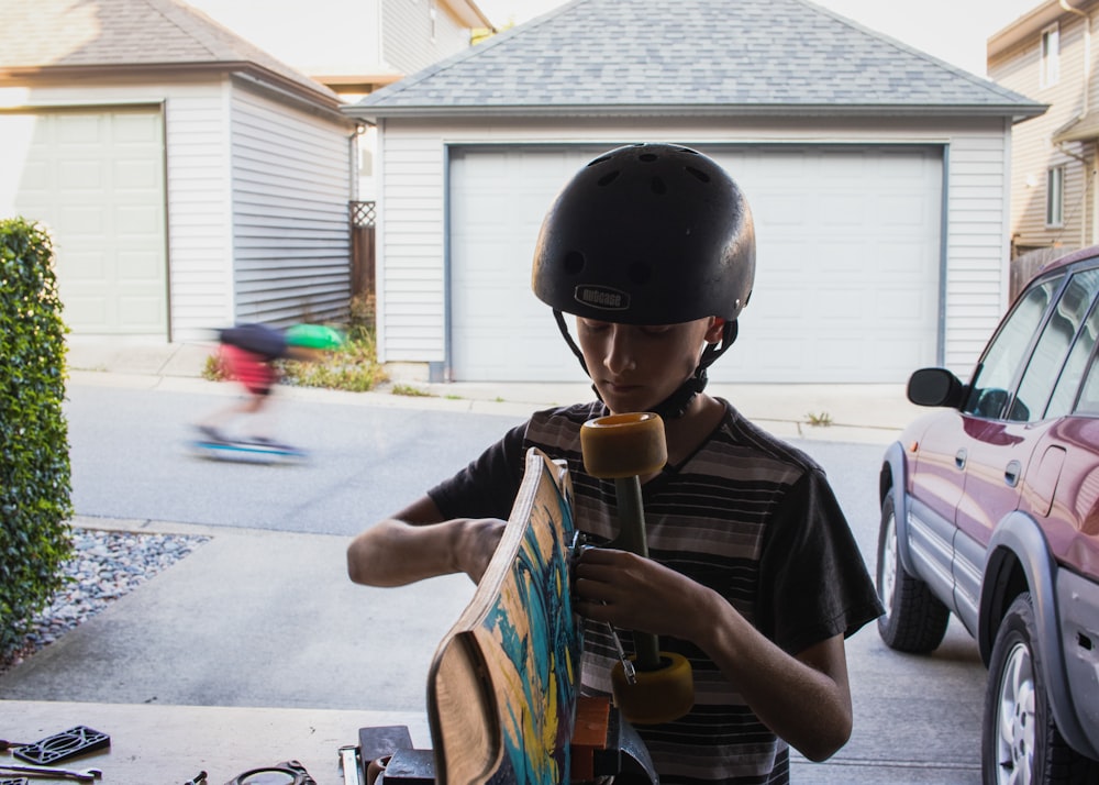 boy in black crew neck t-shirt playing brown acoustic guitar