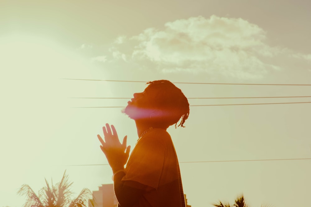 woman in brown coat raising her hands