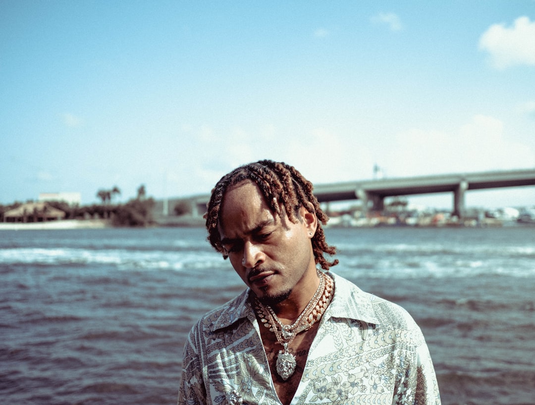 man in gray and white button up shirt standing near body of water during daytime