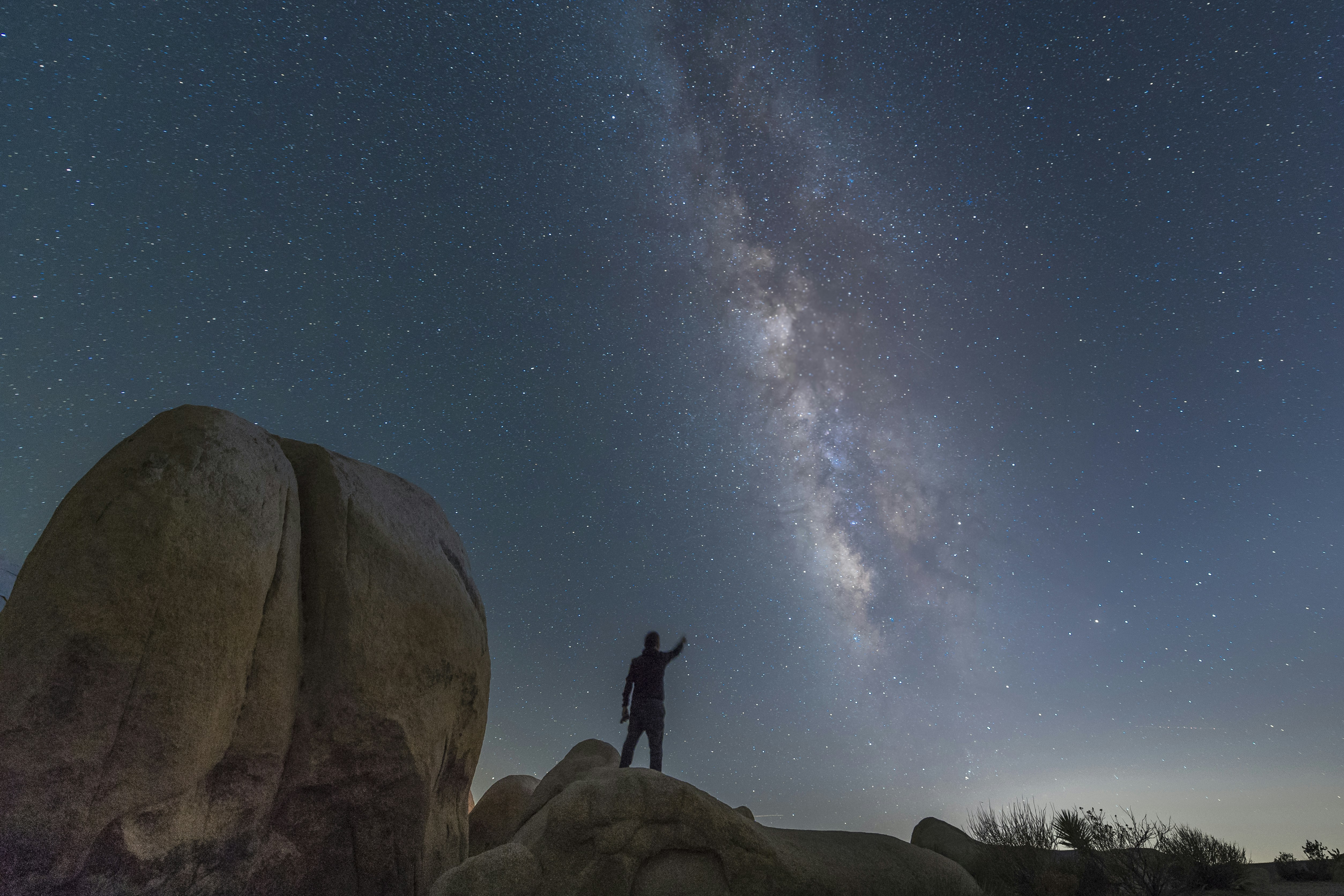man standing on rock formation under blue sky during daytime, 
