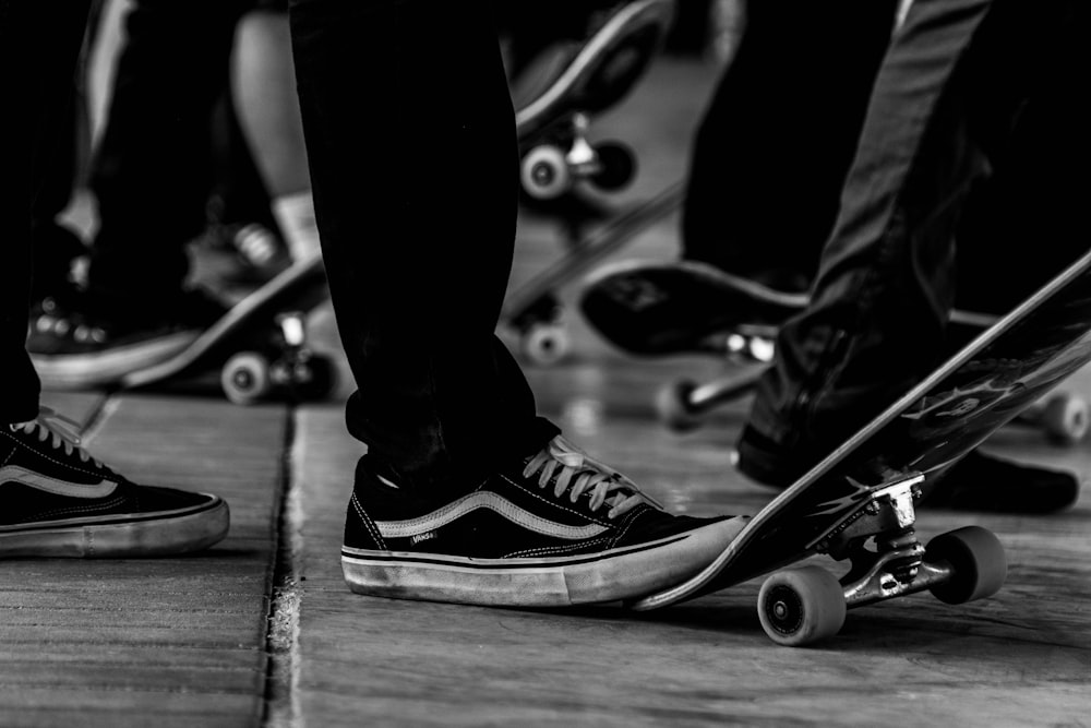 grayscale photo of person wearing black and white converse all star high top sneakers