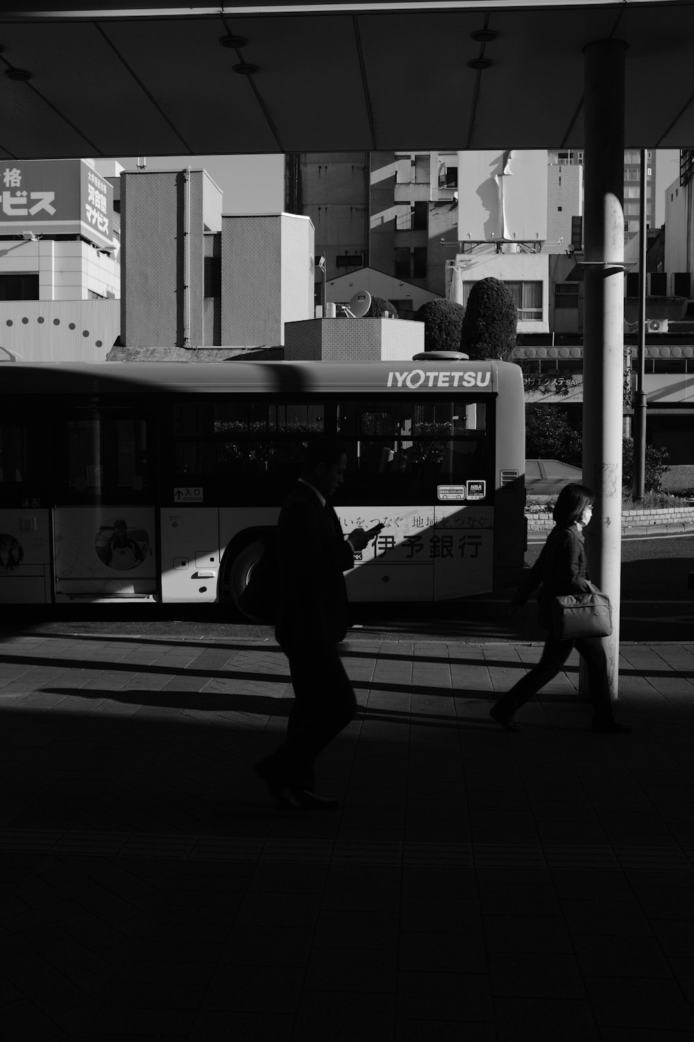 grayscale photo of man walking on pedestrian lane