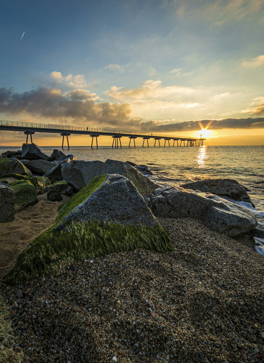 brown wooden bridge over the sea under white clouds