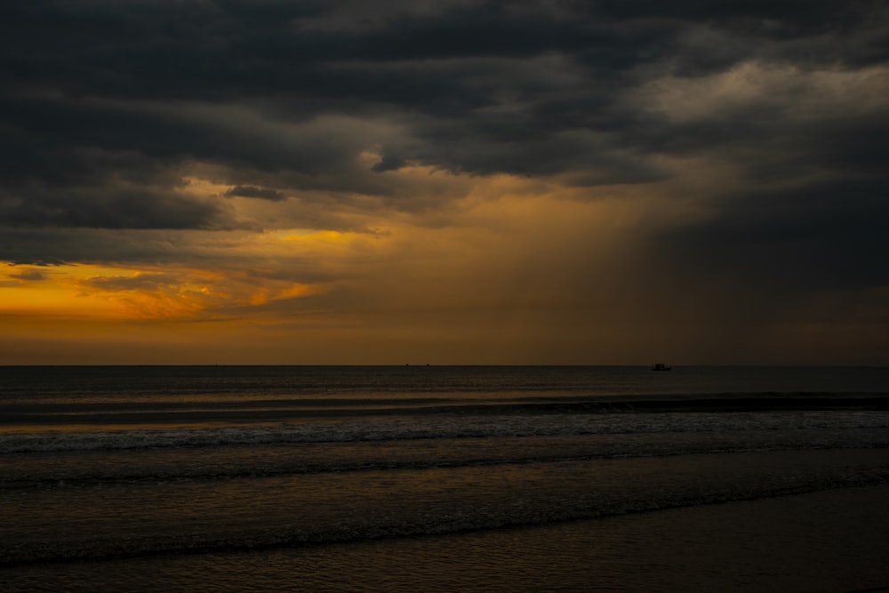 body of water under cloudy sky during sunset