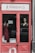 A storefront display with a red-framed glass door. Visible are mannequins dressed in elegant gowns, one in a red dress and the other in a black one. The name 'Marina D.' is prominently displayed above the door. Sticker labels for payment options are affixed to the door, and a car is partially visible reflected in the glass.