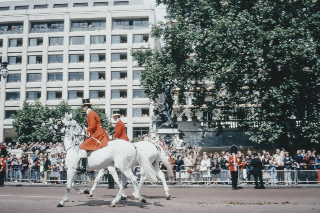 people riding horses near white concrete building during daytime, 1970s film photo