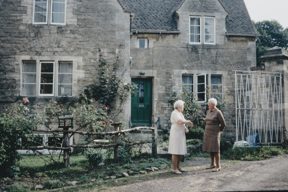 2 women standing in front of brown brick building during daytime