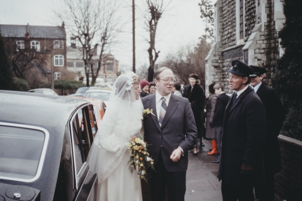 bride and groom walking on sidewalk during daytime