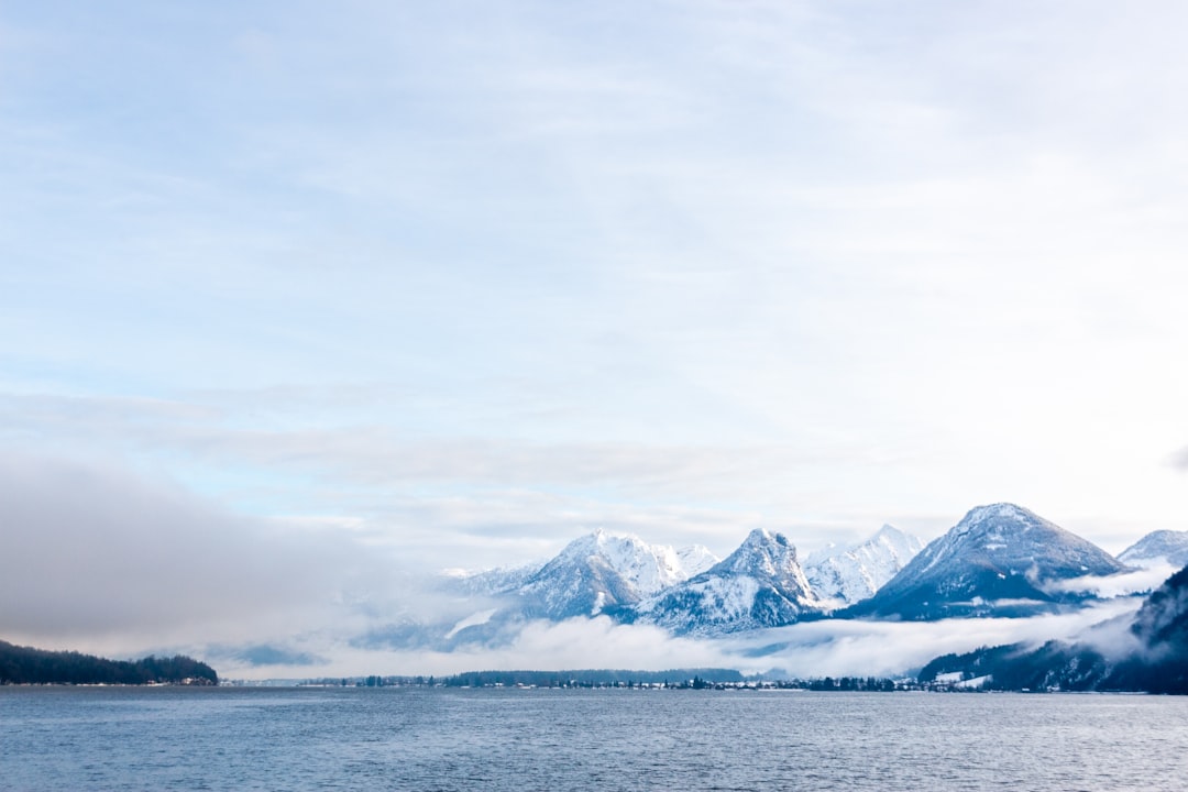 snow covered mountain near body of water during daytime