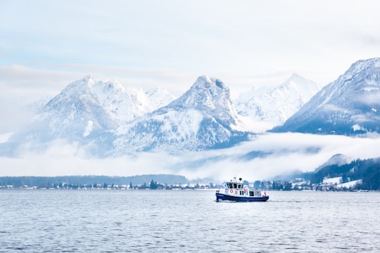 white and black boat on body of water near snow covered mountain during daytime in Sankt Gilgen Austria