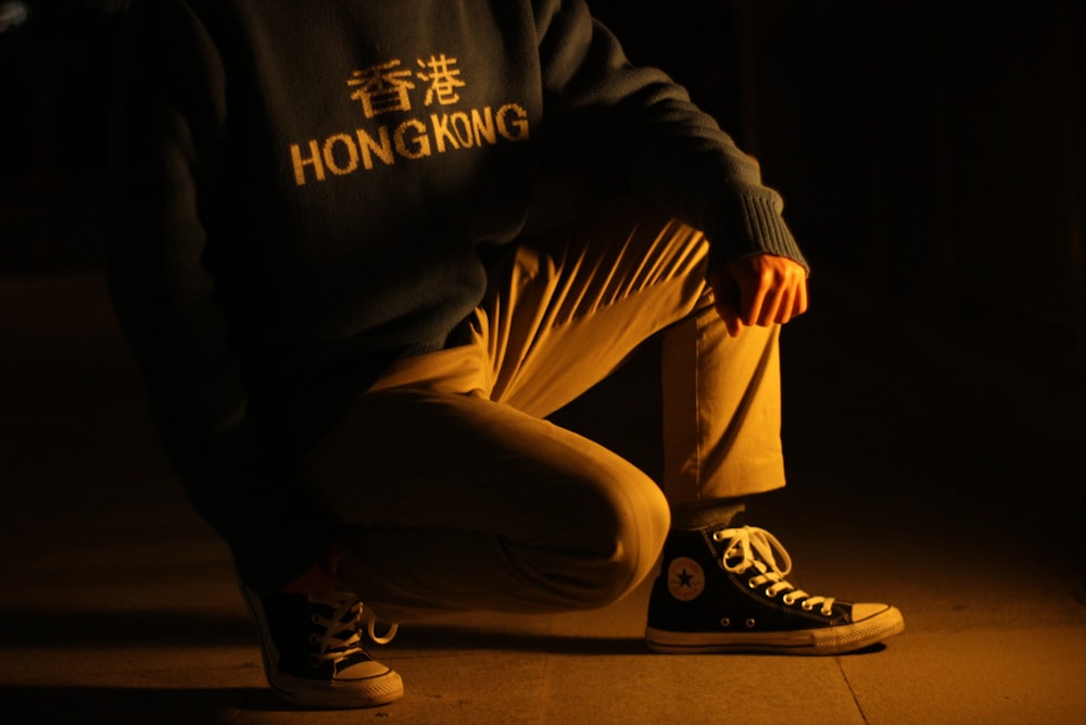 person in black and white long sleeve shirt and brown pants sitting on floor