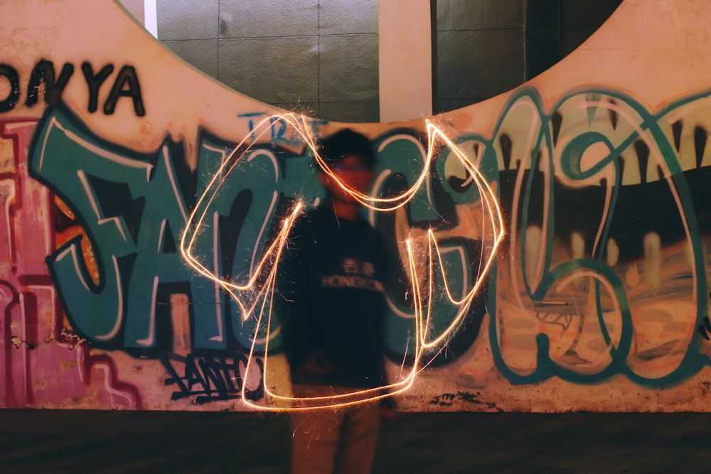 Femme en chemise noire debout près d’un mur de graffitis